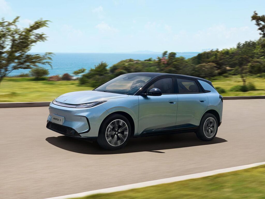Front three quarter view of a blue ARCFOX T1 electric SUV driving by the ocean