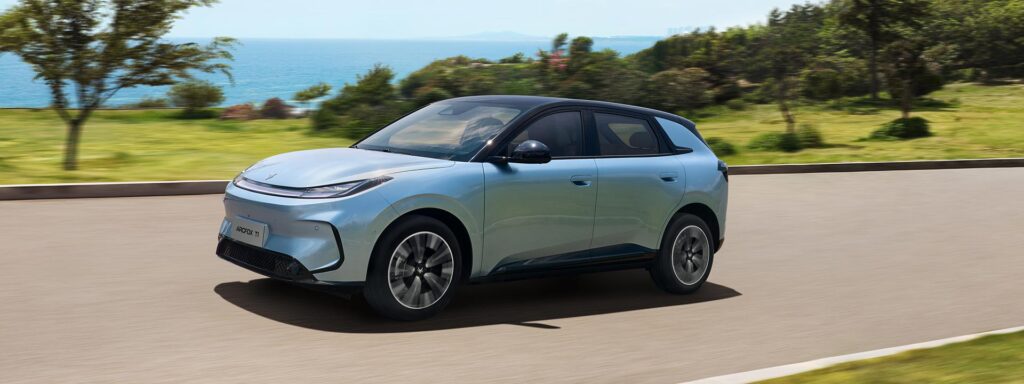Front three quarter view of a blue ARCFOX T1 electric SUV driving by the ocean