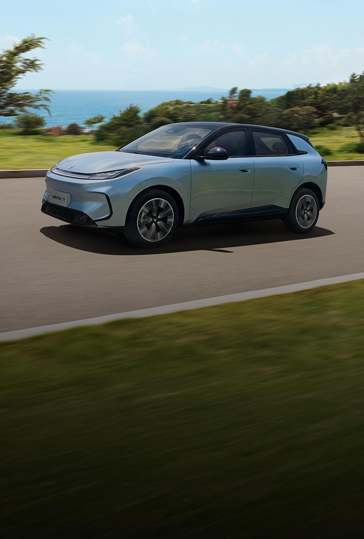 Front three quarter view of a blue ARCFOX T1 electric SUV driving by the ocean