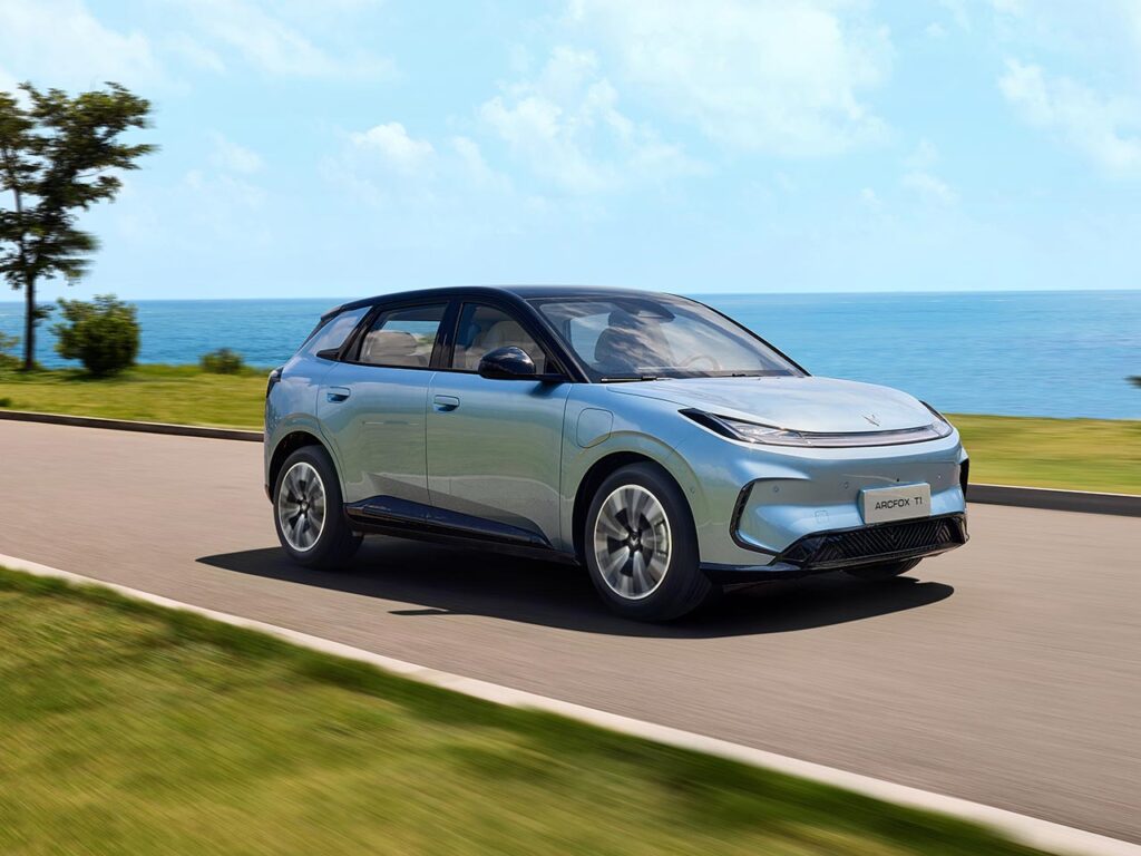 Front three quarter view of a blue all-electric ARCFOX T1 SUV driving next to the ocean
